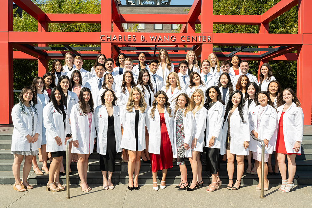 Four rows of students wearing white coats