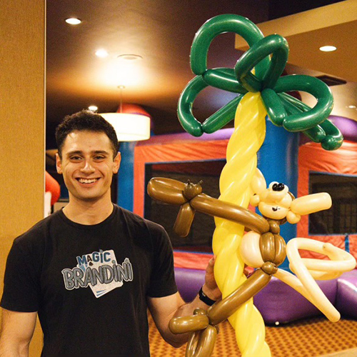 Dental student with balloon creation depicting a monkey climbing a palm tree