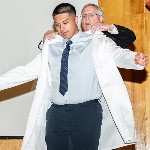 Student putting on a white coat
