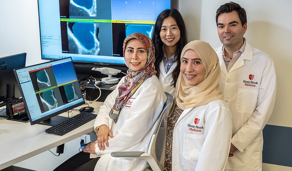 Radiology residency director and residents posing in front of a laptop and larger screen showing imagery