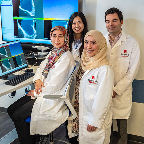 Radiology residency director and residents posing in front of a laptop and larger screen showing imagery