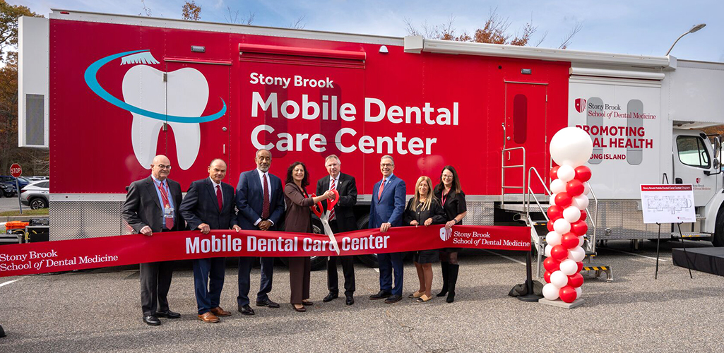 Administrators, faculty and staff cutting a ribbon in front of the new Mobile Dental Care Center
