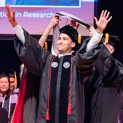 School of Dental Medicine graduate raises his arms in triumph