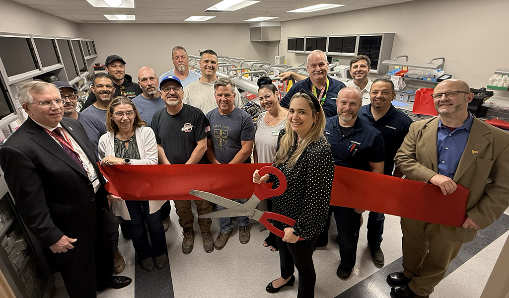 Administration, faculty and staff standing in new prosthodontics lab with scissors and red ribbon to commemorate its opening