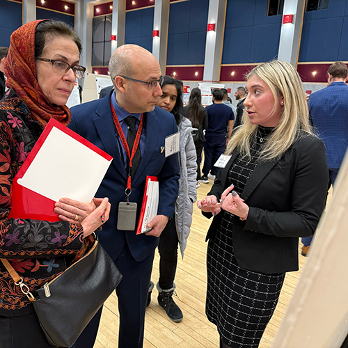 Dental student sharing information on her presentation to two faculty members.