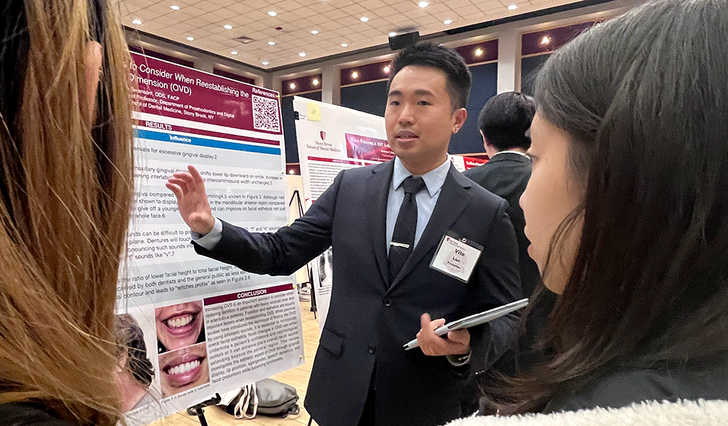 Student Vito Liut presenting his research to two guests at Stony Brook School of Dental Medicine Research Day