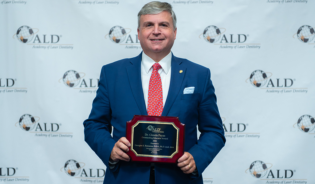 Georgios Romanos holding his award from the Academy of Laser Dentistry