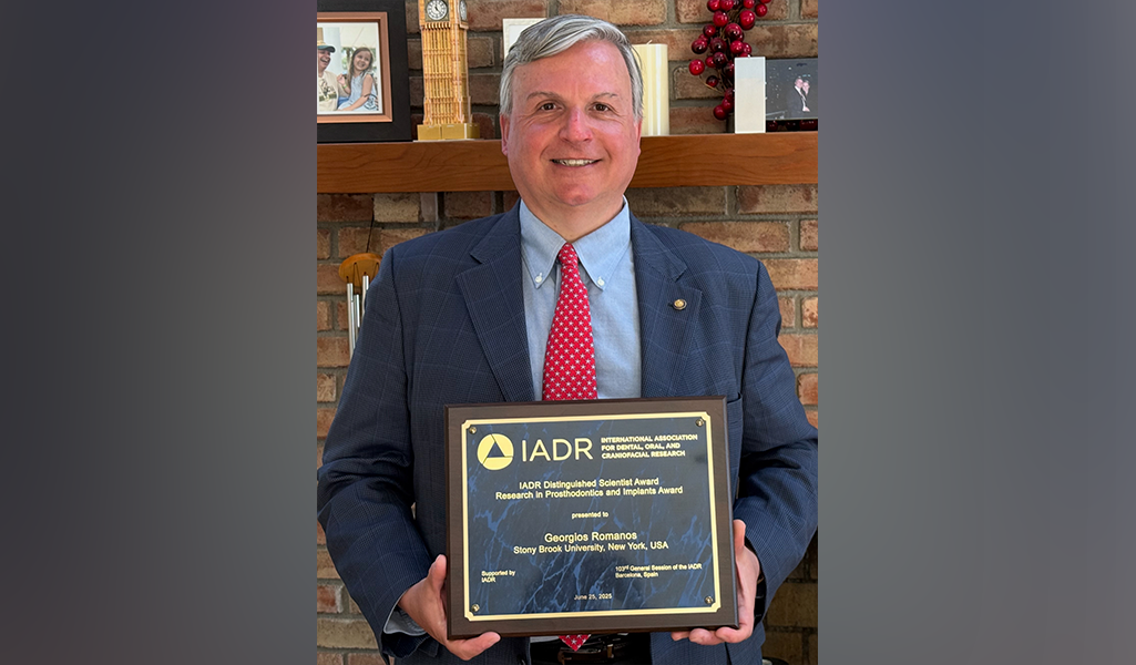 Georgios Romanos holding his IADR award