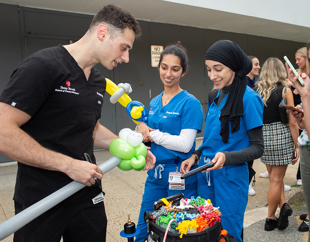Dental student creating balloon animals for interested students.