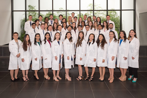 Group photo of Stony Brook School of Dental Medicine's Class of 2022 in their white coats. 