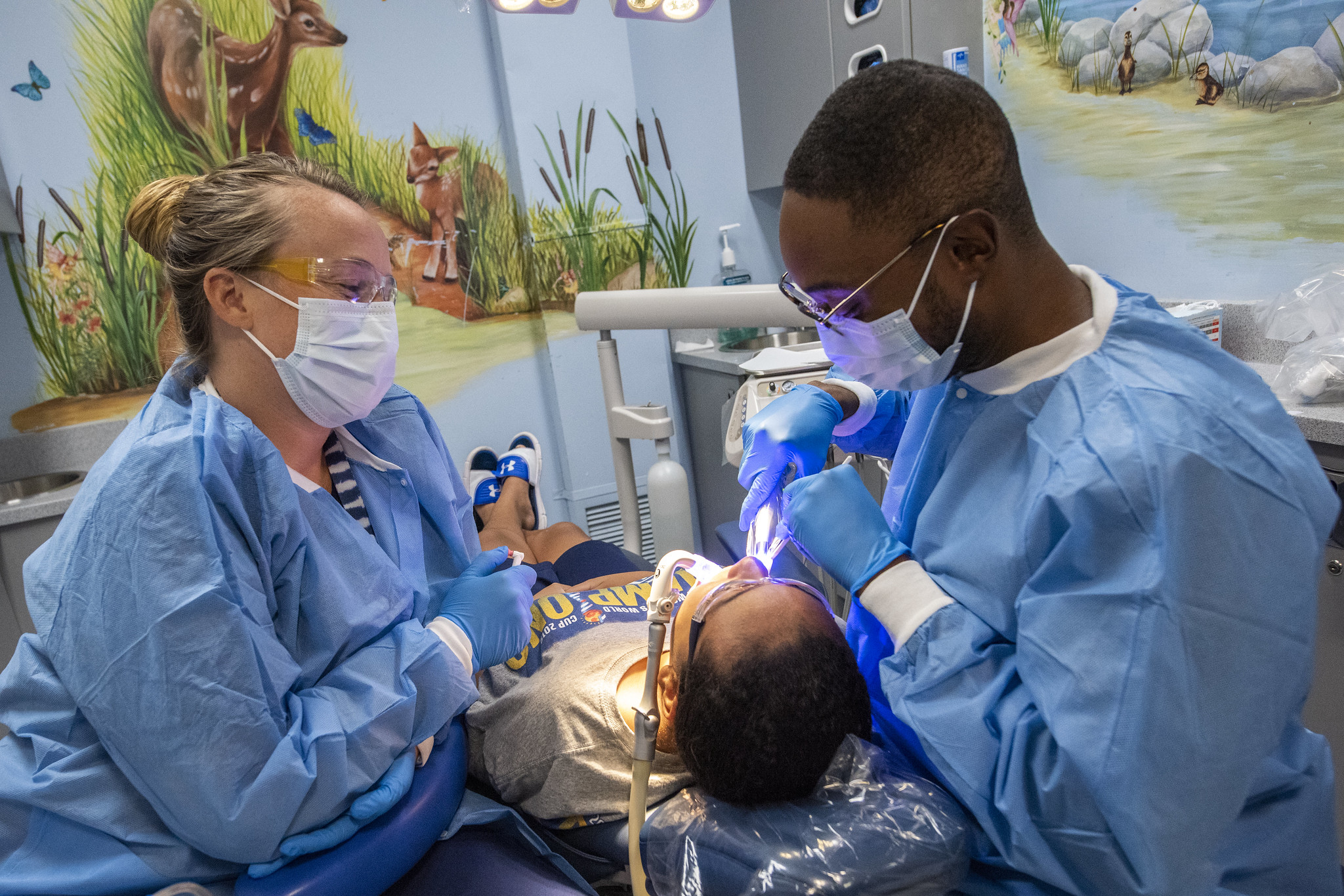 Drs. Lauren Heisinger and Sean Challenger provide oral healthcare treatment to a children at Stony Brook School of Dental Medicine.