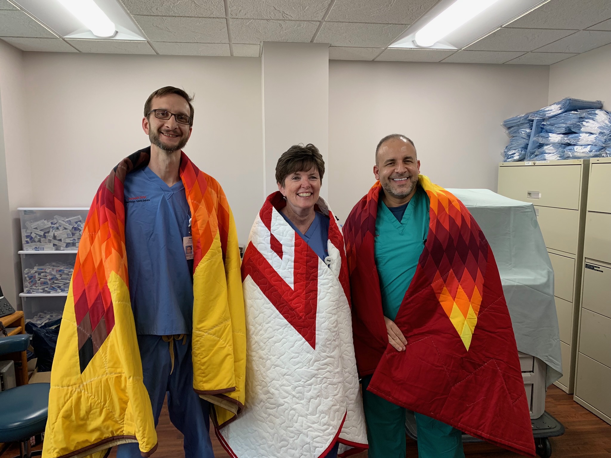 Dr. Mary Truhlar, Dean, and Dr. John Foti, Clinical Assistant Professor wearing star quilts that they received as a gift from the Pine Ridge Indian Health Services Hospital