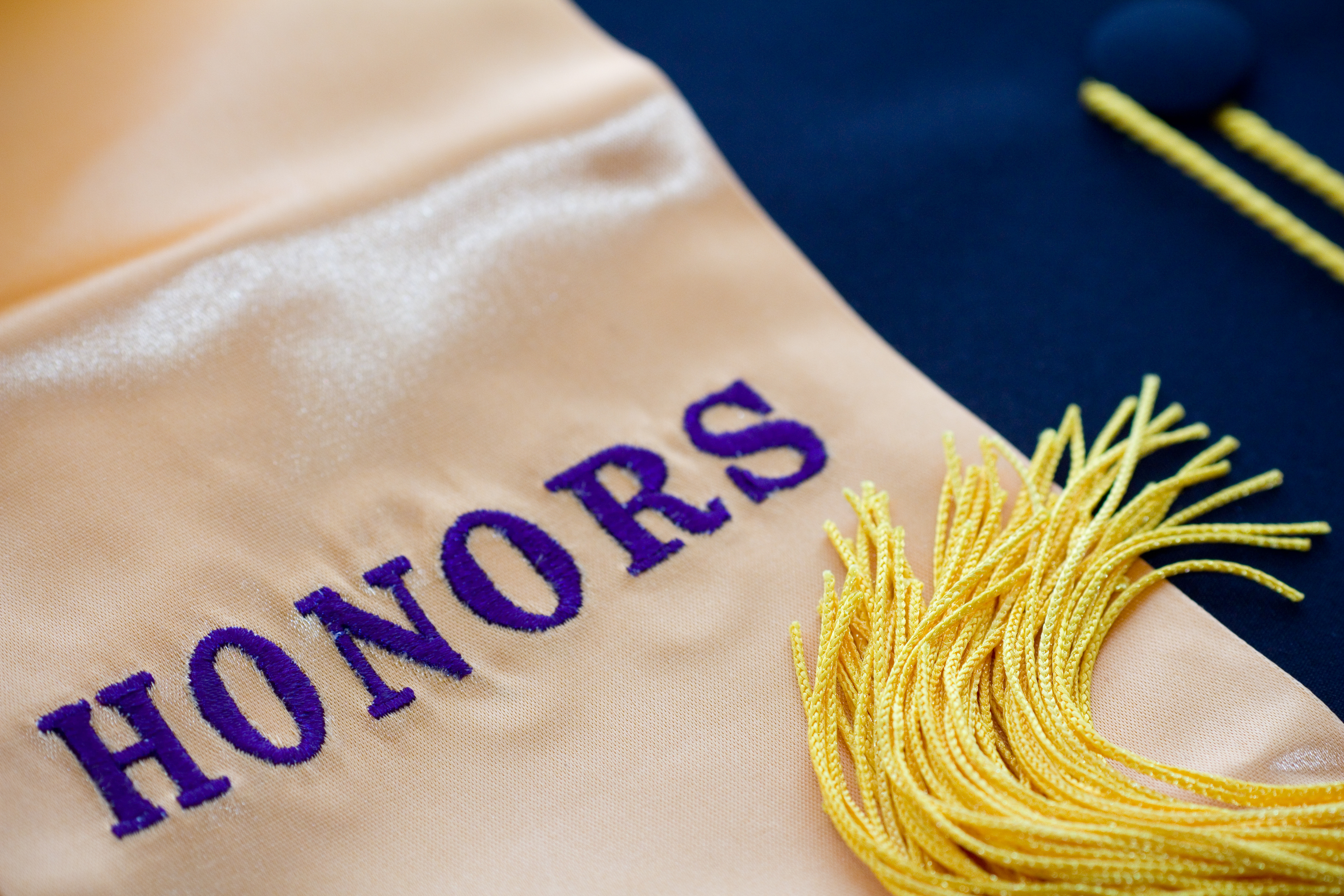 "HONORS" written on a graduation stole with a yellow tassel laid over the fabric.