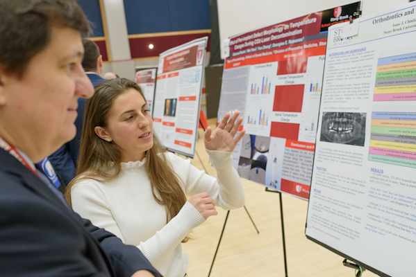 Student Heather Ercolano explains her research to Dr. Wellington Rody at the Stony Brook University School of Dental Medicine's 2019 Leo and Mickey Sreebny Lectureship and School of Dental Medicine Research Symposium